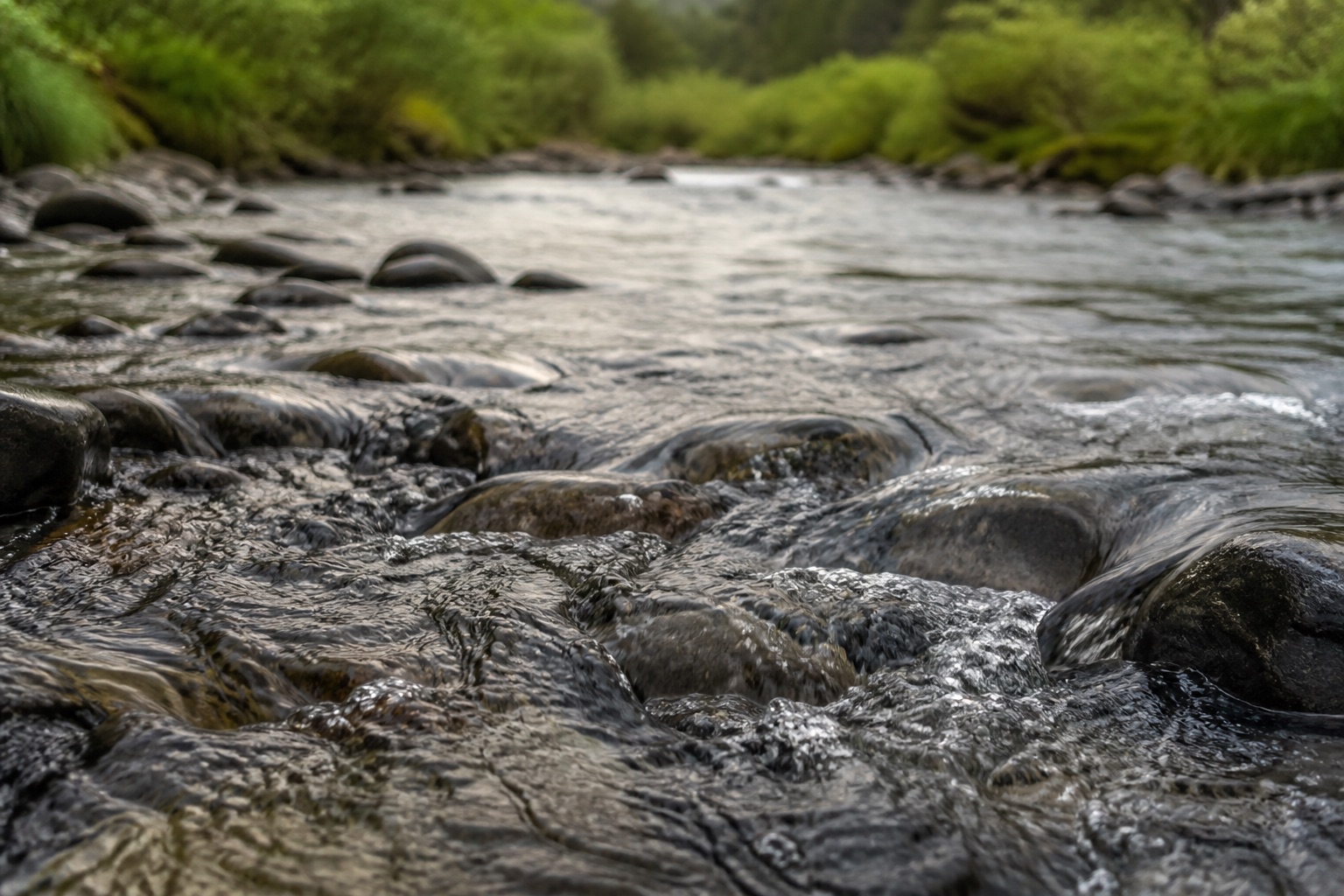 Clear water moving steadily over smooth river stones